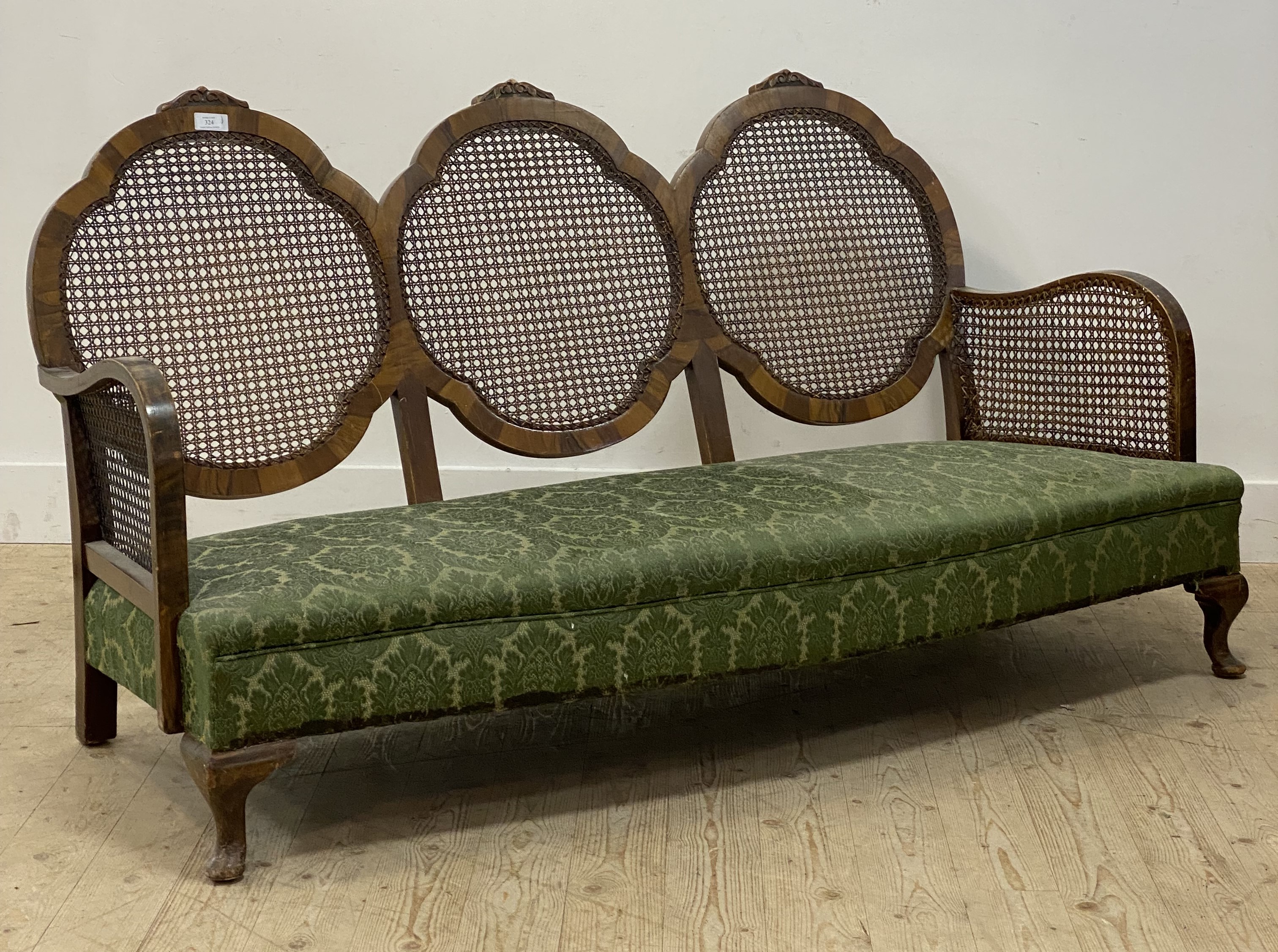 A 1930's walnut framed bergere three seat sofa, with cane panelled back and sides, raised on