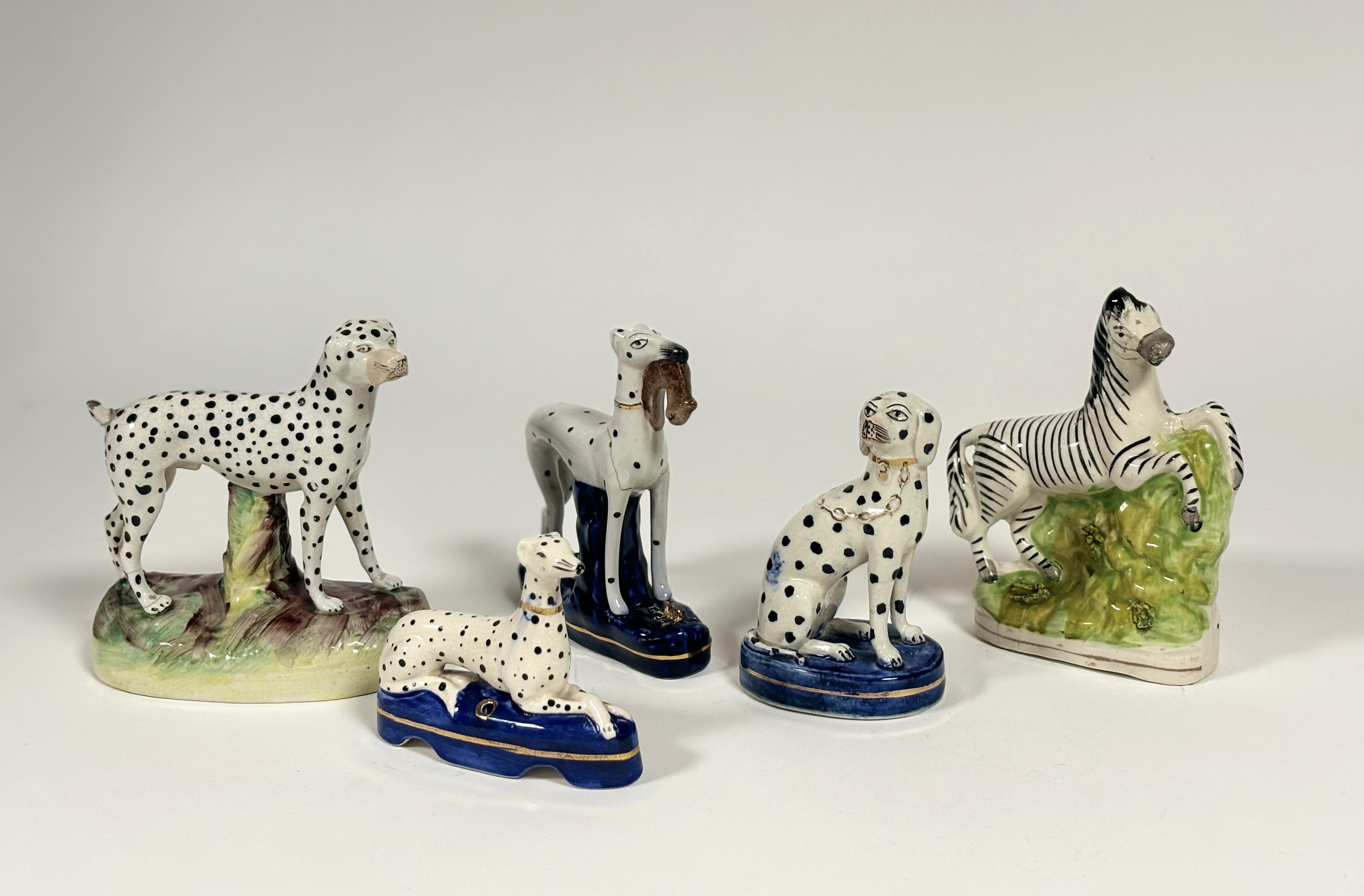 A group of five Staffordshire models, 19th century and later, comprising: a flatback prancing zebra;