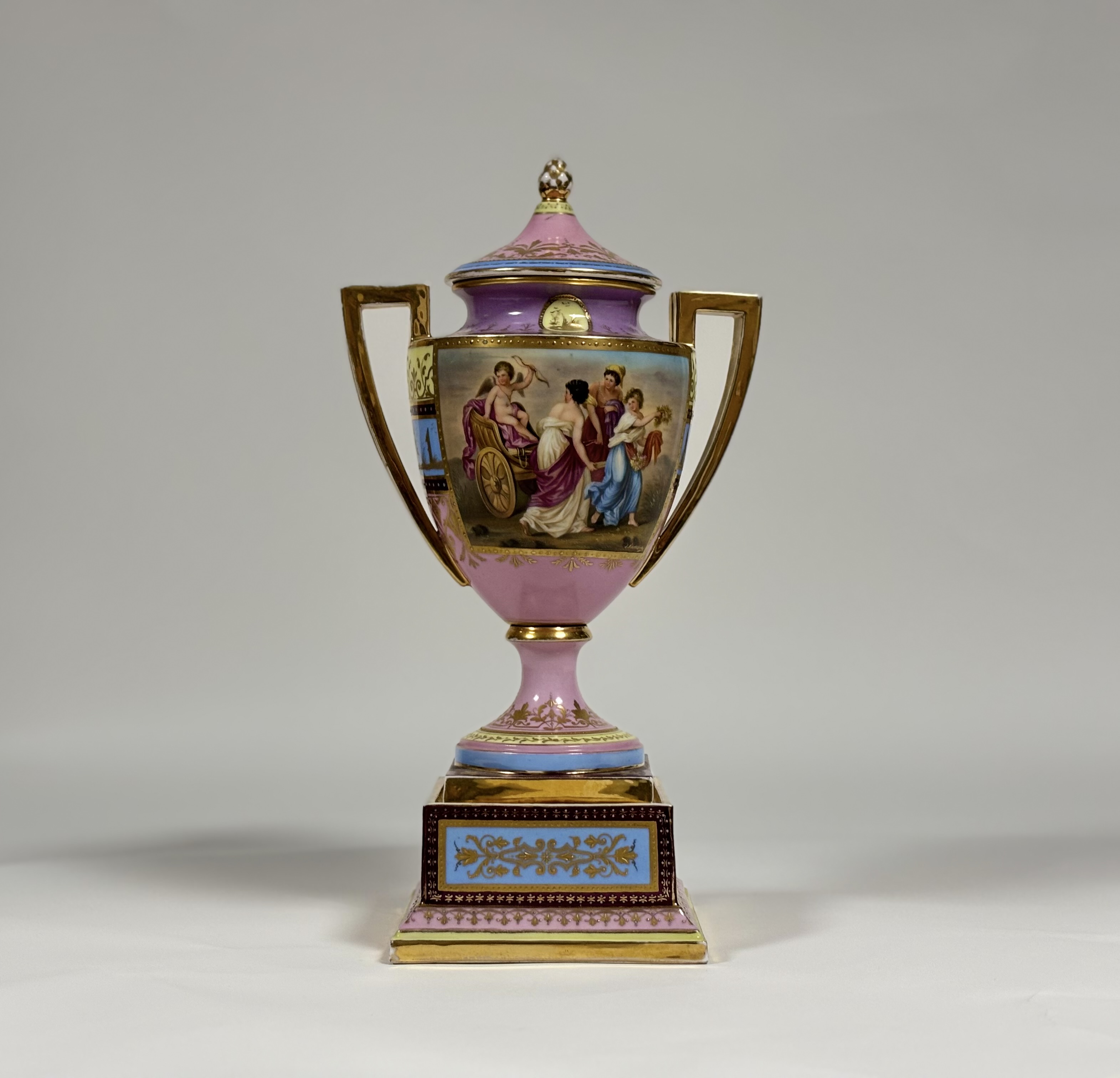 A late 19th century Vienna porcelain covered urn on stand, of hipped baluster form, painted with a