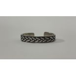 Patrick Mavros, a sterling silver bangle, repousse with a chevron pattern against a blackened