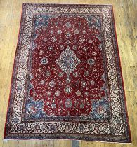 A Persian Tabriz rug, the red field with central medallion and interlaced trailing foliate, enclosed