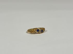 An Edwardian 18ct gold sapphire and diamond ring, the scroll-form plaque set to the centre with a