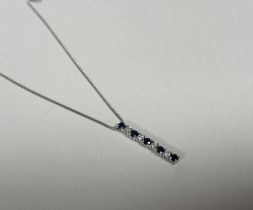 A sapphire and diamond bar pendant, formed of an articulated line of five round-cut sapphires and