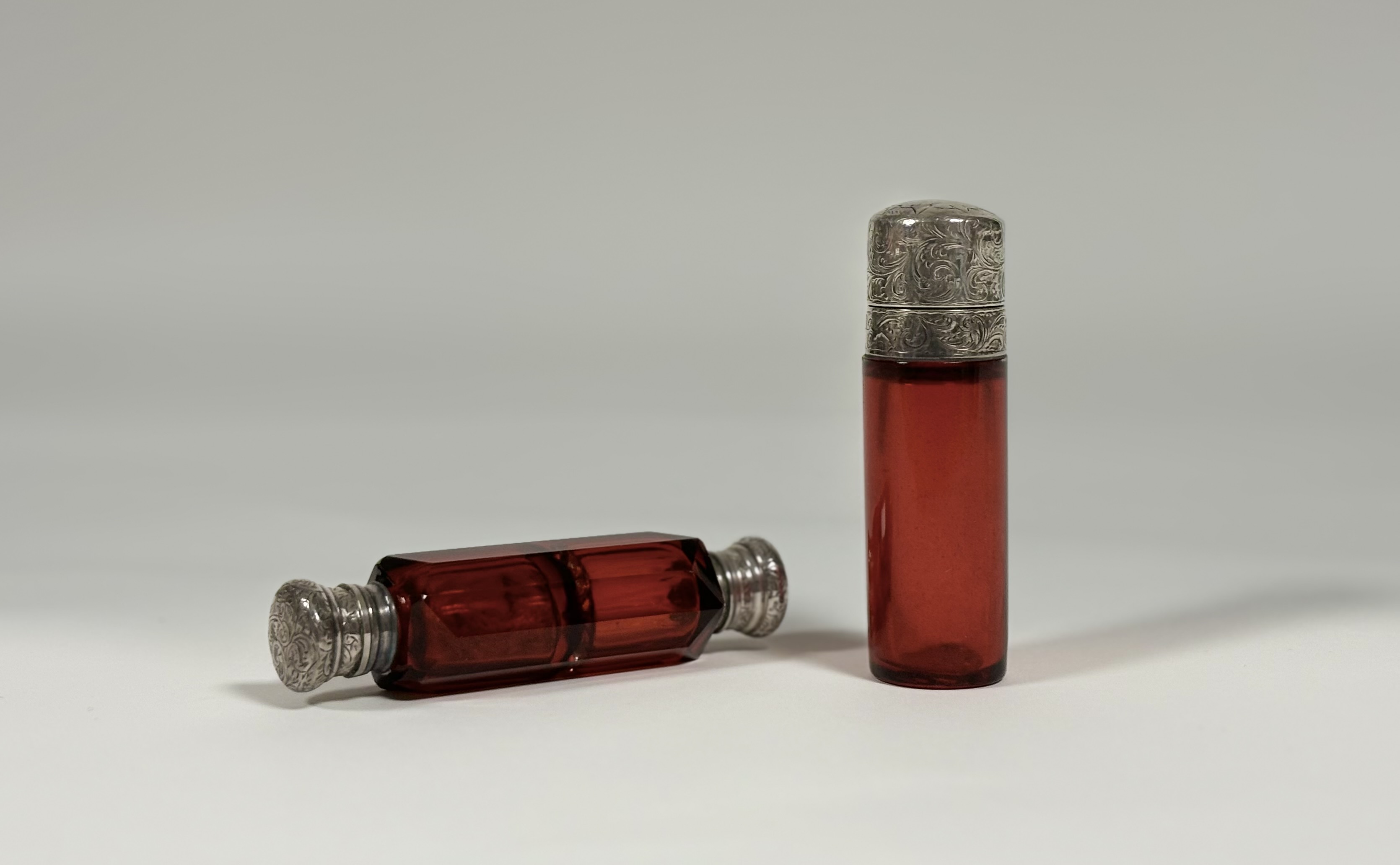 Two late 19th century ruby glass scent bottles: the first double-ended in faceted glass with