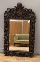 A Black Forest oak wall-hanging mirror, late 19th century, the frame profusely carved with masks and
