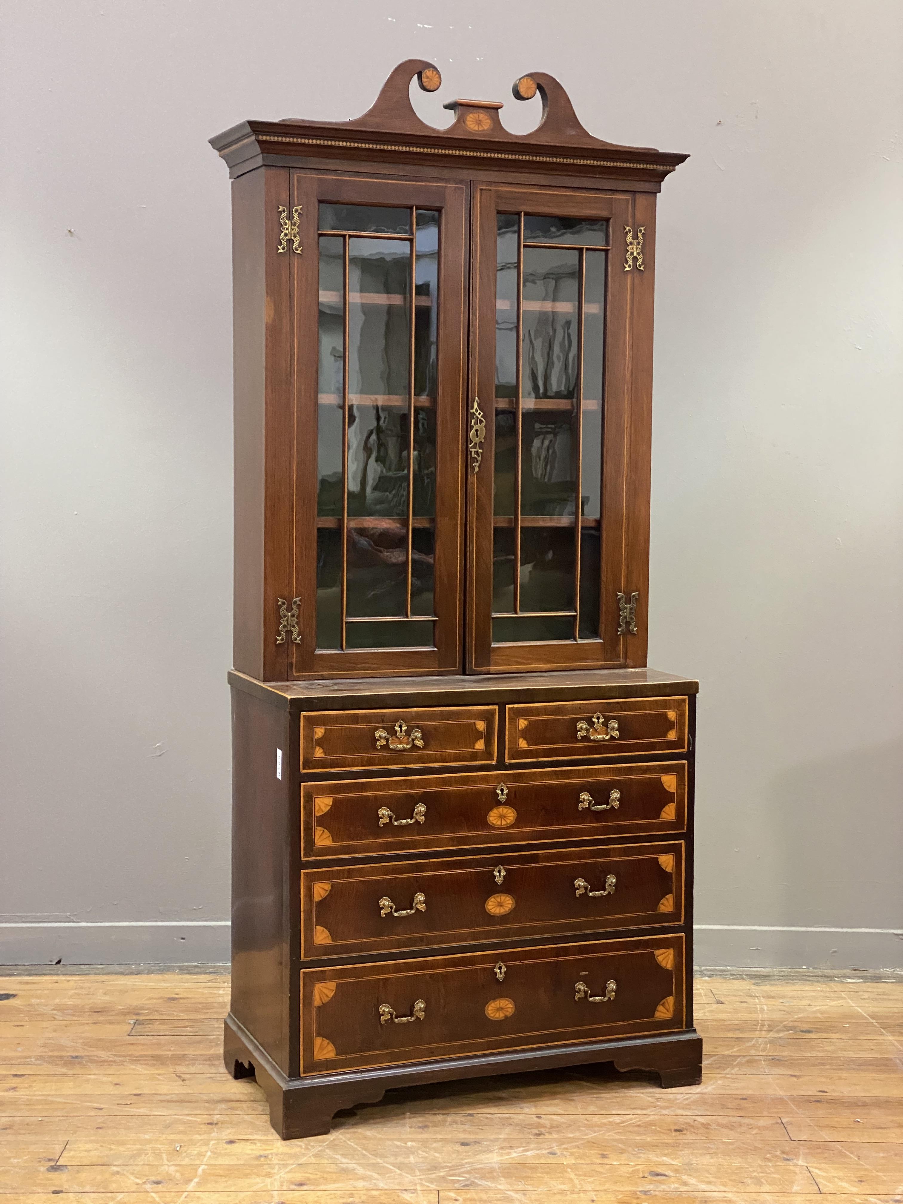 A George III mahogany bookcase on chest, the swan neck pediment with boxwood paterae, above two