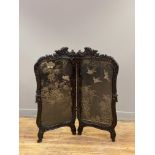 A late 19th century twin panel low screen, the ebonised frame carved with scrolling acanthus,