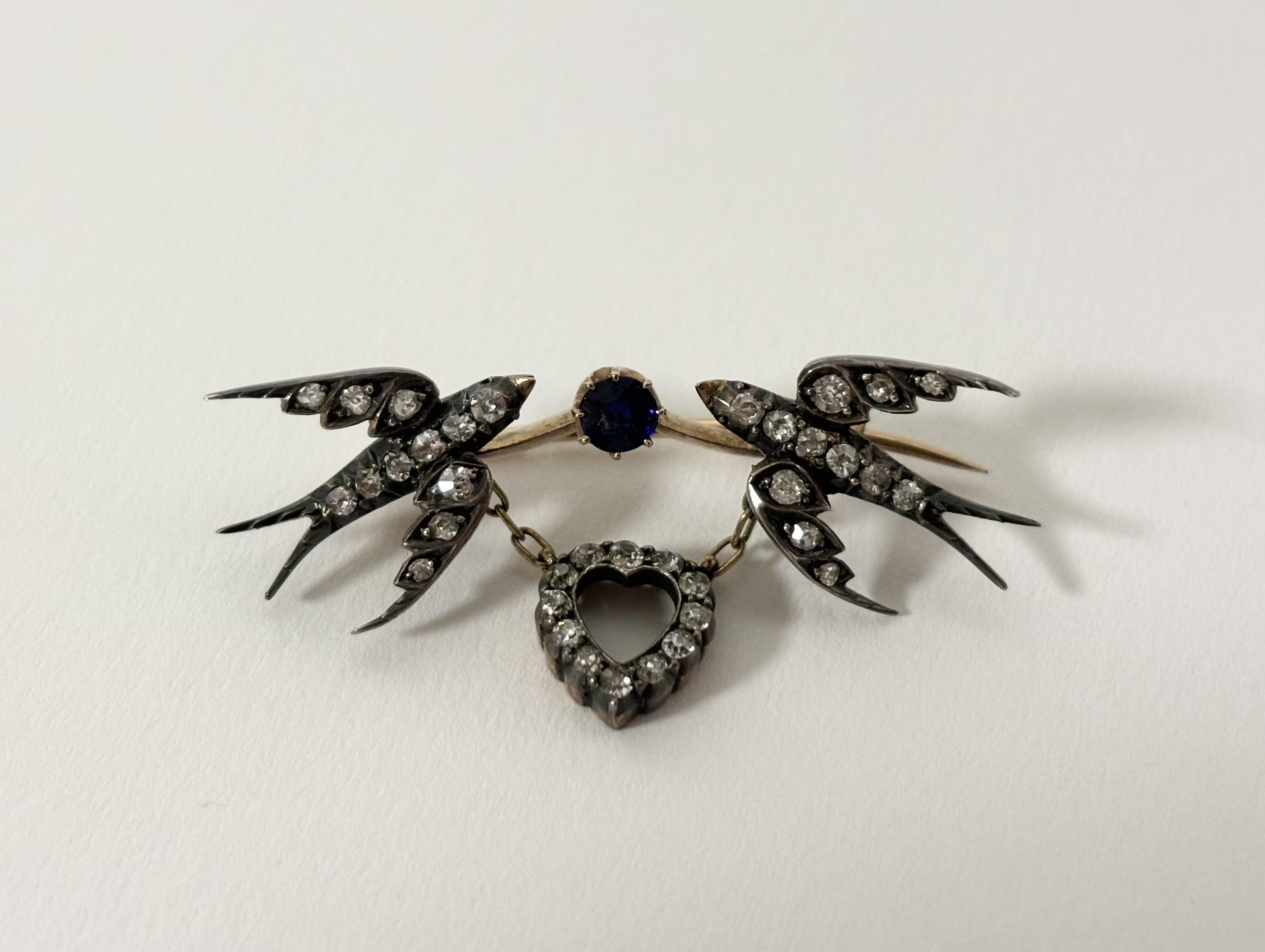 A late Victorian diamond and sapphire brooch modelled as a pair of swallows suspending a heart, - Image 2 of 3
