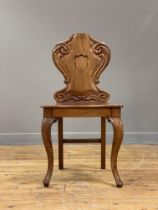 A Victorian mahogany hall chair, the scroll carved back of cartouche form above a panel seat with