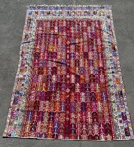 A large hand knotted Caucasian carpet, decorated with repeating motifs in a vibrant palette. (