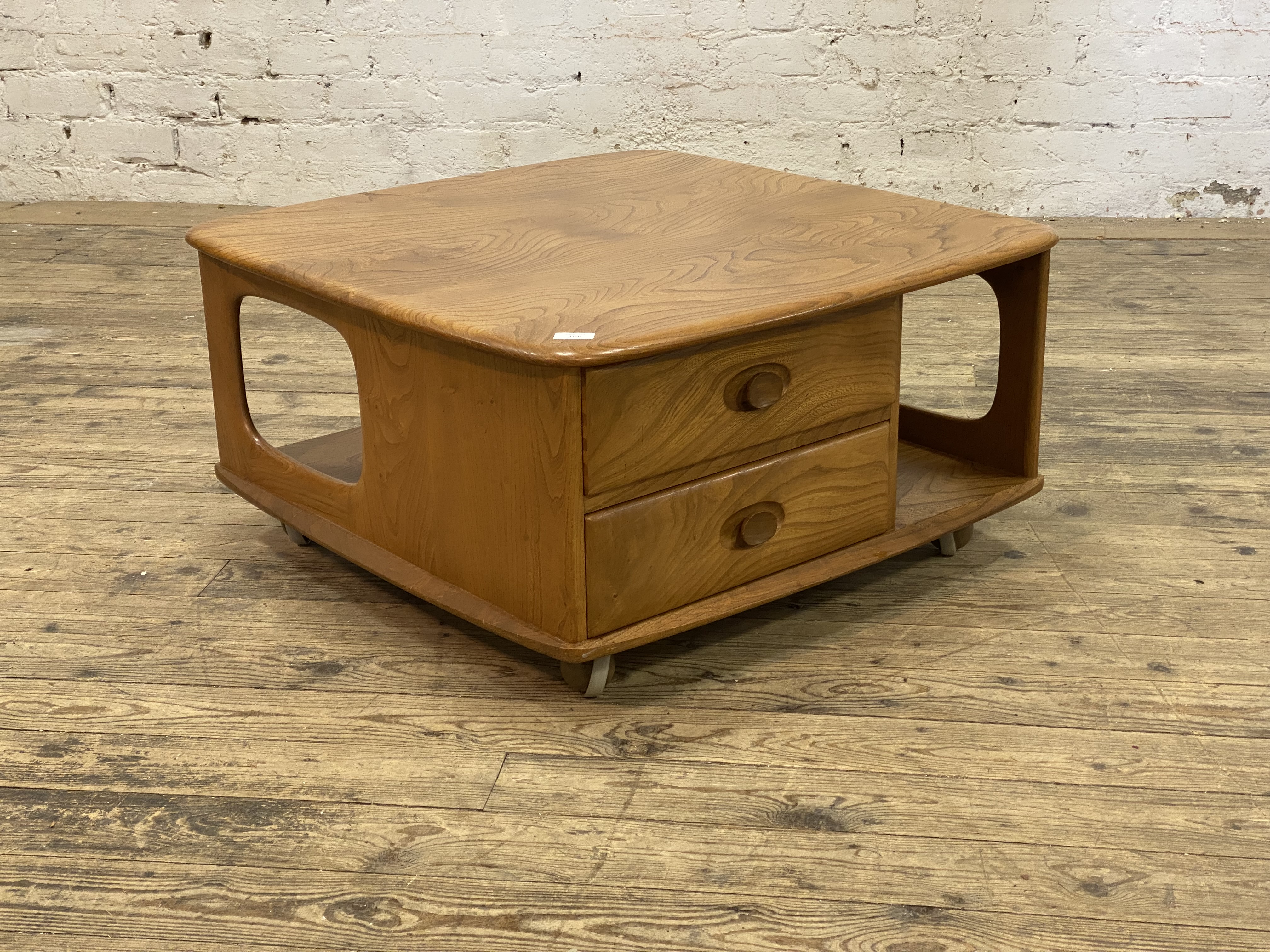 Ercol, an elm coffee table, the shaped square top above two drawers and an under tier, all moving on