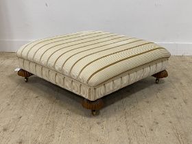 A large traditional footstool of square form, over stuffed upholstery covered in stripped ivory