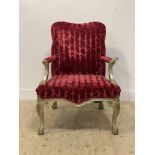 A French style open armchair, the silvered frame enclosing red velvet upholstery, raised on cabriole
