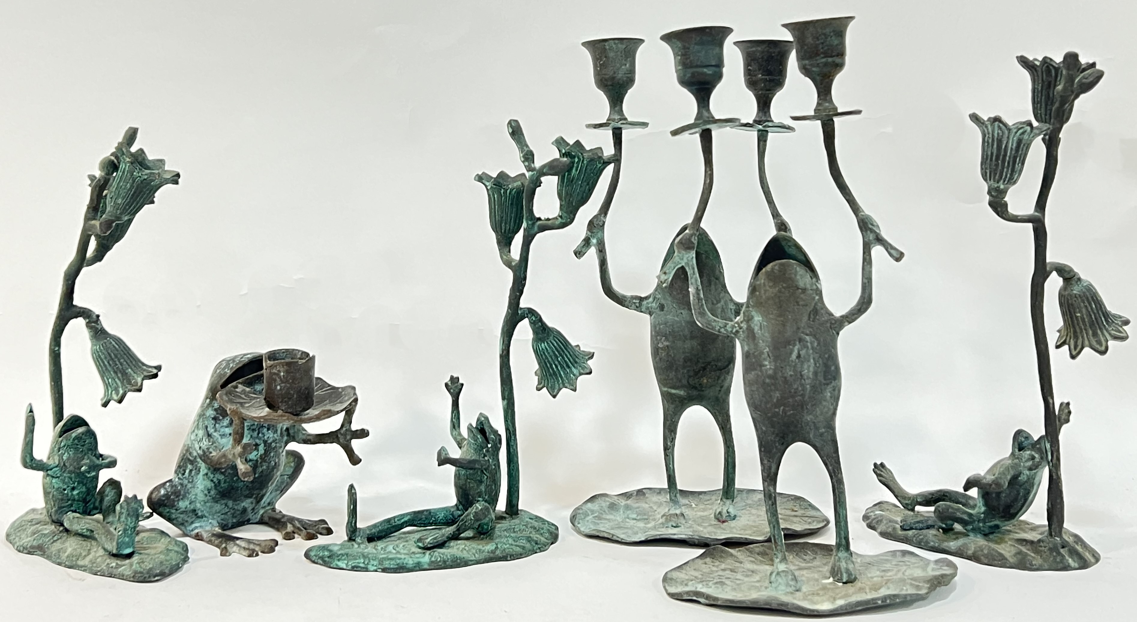 A group of bronze candle holders modelled as frogs comprising a pair of double candle holders, three