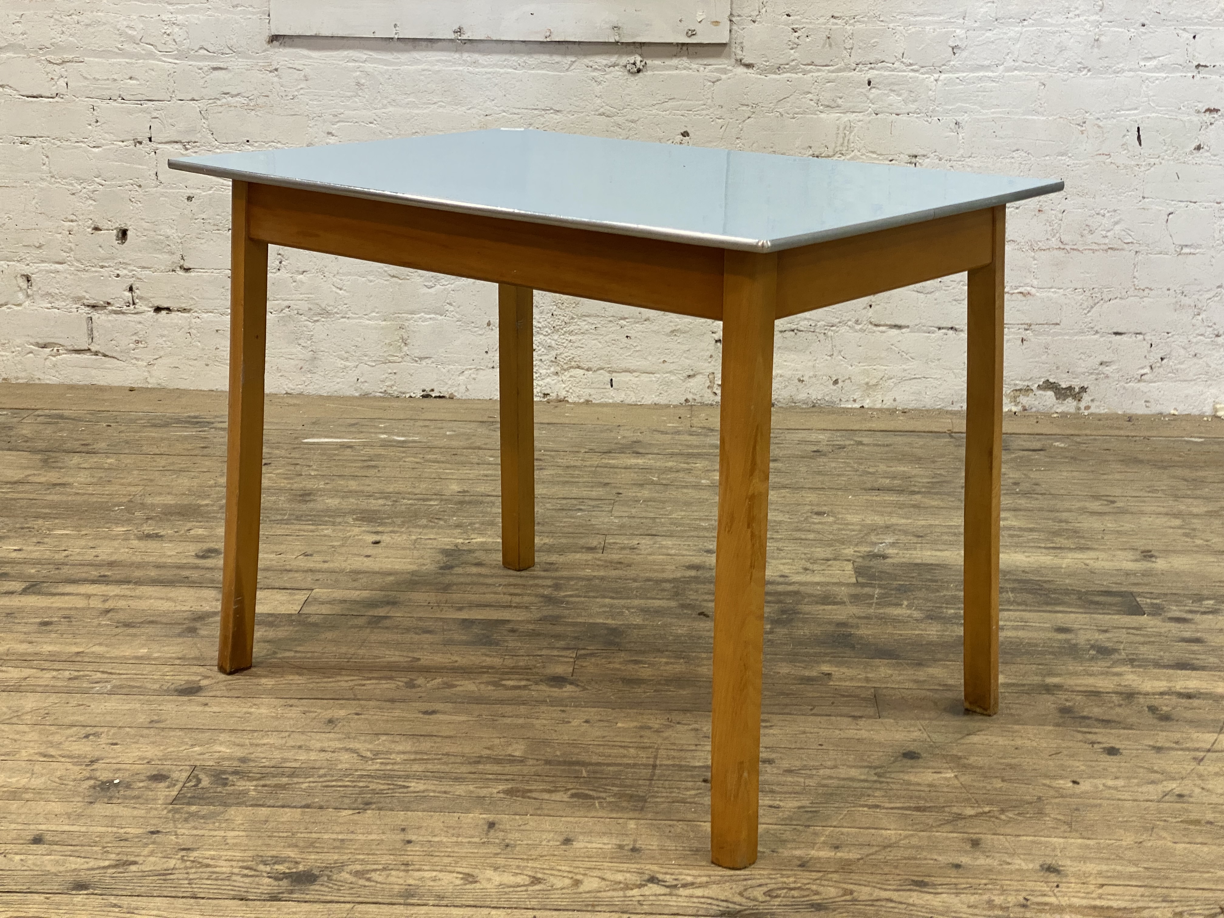 A mid century kitchen dining table, with blue formica top raised on splayed beech supports. H76cm,