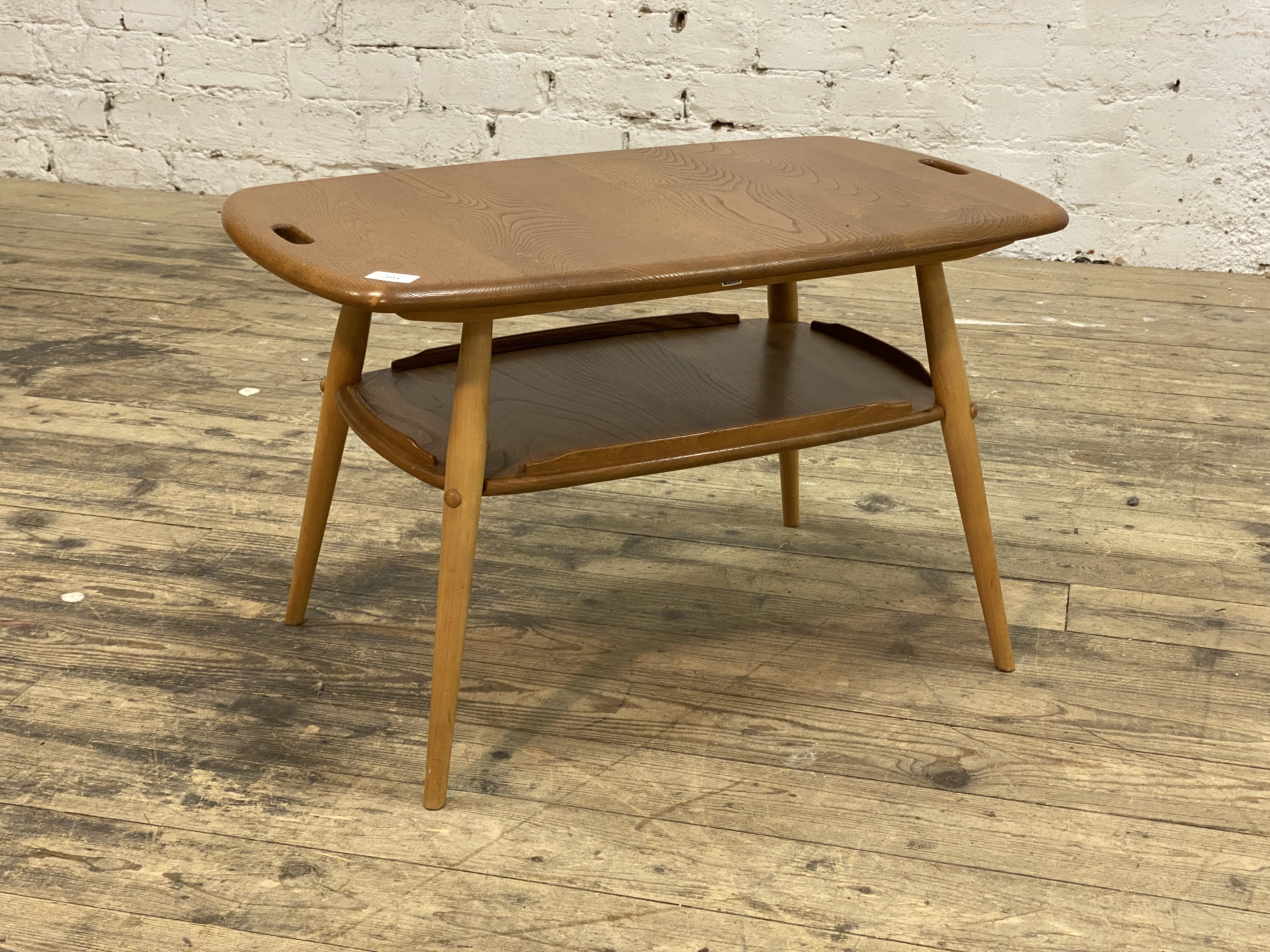 Ercol, an elm coffee table, the shaped top with pierced handle to each end, raised on turned and