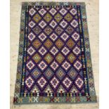 A kilim rug, in purples, blues, greens, and reds. 253cm x 167cm.