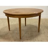 A mid century teak circular dining table with magic leaf to centre and raised on turned and
