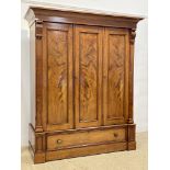 A Victorian mahogany wardrobe, the projecting cornice above three well figured and panelled doors,