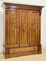 A Victorian mahogany wardrobe, the projecting cornice above three well figured and panelled doors,