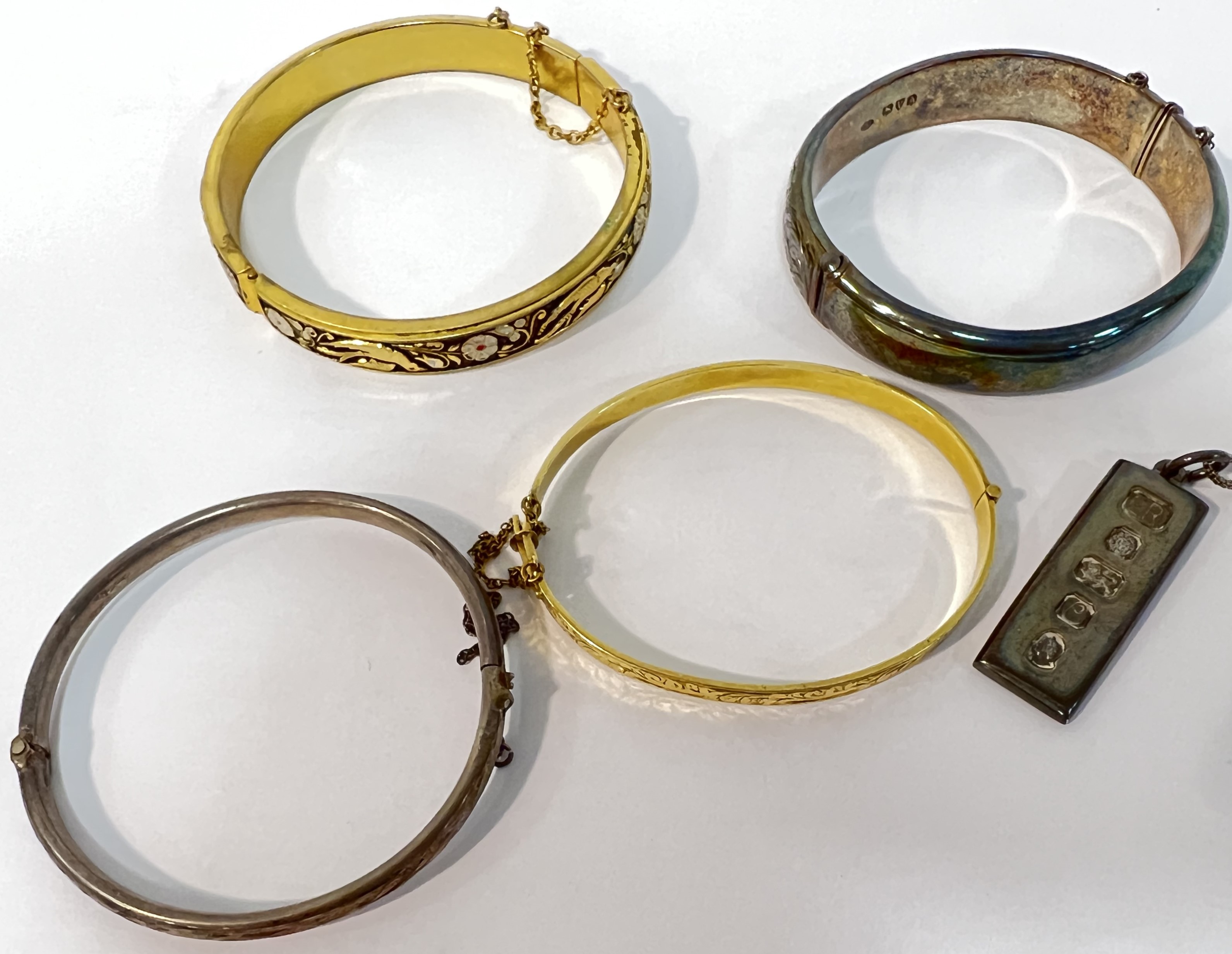 A group of four bangles comprising a Smith and Ewen Chester hallmarked silver bangle, two gold