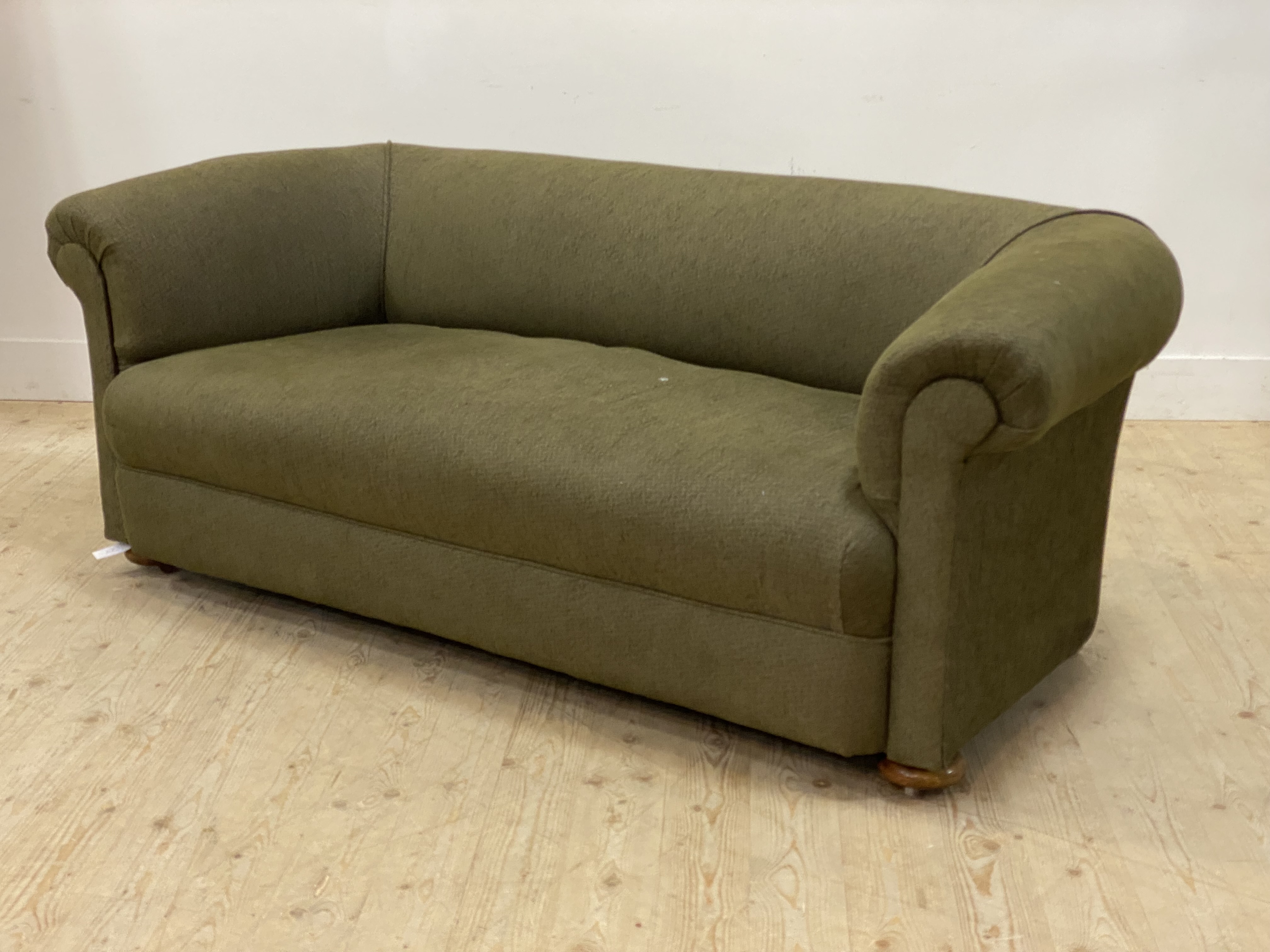 An early 20th century Chesterfield sofa, upholstered in green, and raised on compressed bun supports