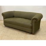 An early 20th century Chesterfield sofa, upholstered in green, and raised on compressed bun supports