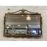 A Neo-classical style gilt framed wall mirror with urn and swag pediment. 98cm x 77cm.