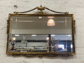A Neo-classical style gilt framed wall mirror with urn and swag pediment. 98cm x 77cm.