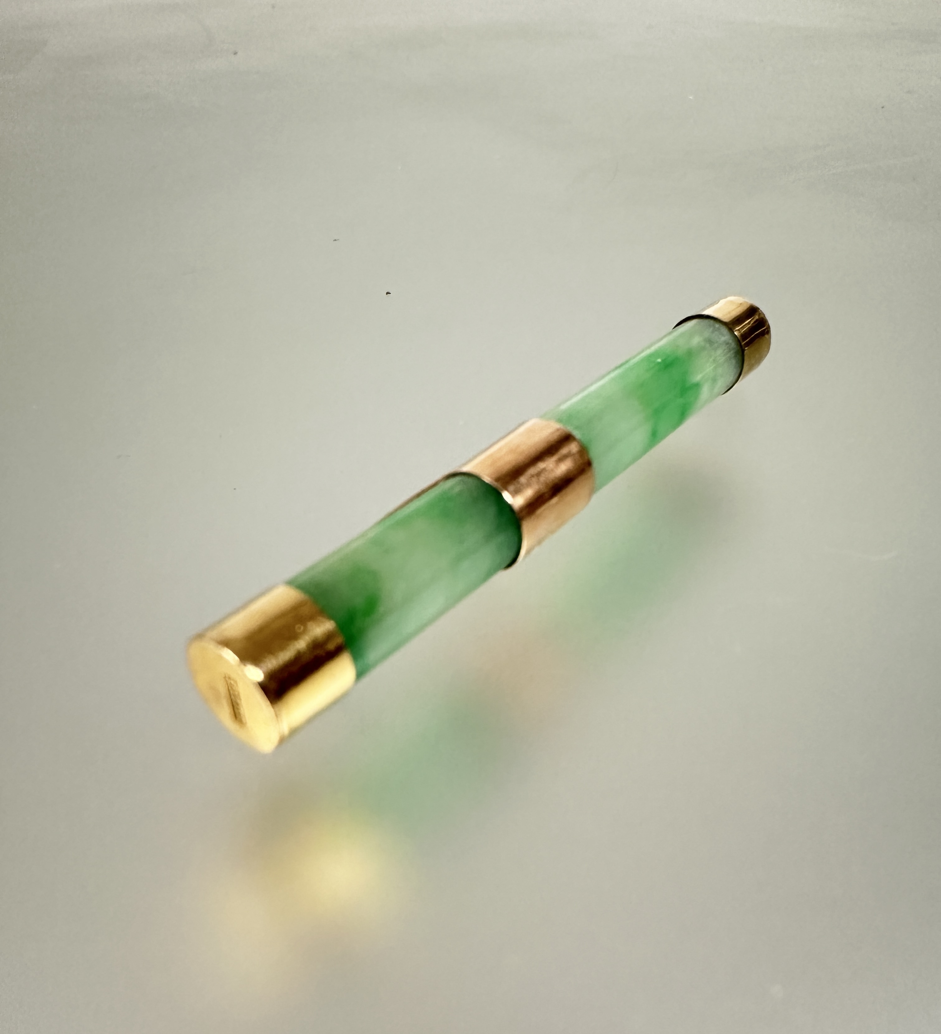 A Chinese 22ct gold mounted celadon jadeite barrel brooch with original clasp fastening shows no