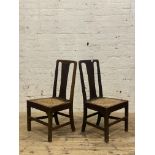 A pair of George III country oak chairs, each with plain splat back over a woven string seat and