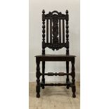 A Carolean style oak chair, carved with floral motifs, with panel seat raised on turned and block