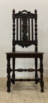 A Carolean style oak chair, carved with floral motifs, with panel seat raised on turned and block