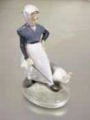 A Danish Royal Copenhagen figure of the goose girl dressed in traditional costume raised on oval