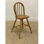 A beech wood child's Windsor high chair, with hoop and spindle back above saddle seat and turned