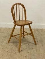 A beech wood child's Windsor high chair, with hoop and spindle back above saddle seat and turned