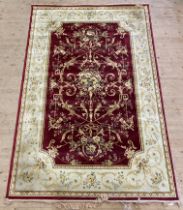 A Machine loomed Persian style silk and cotton rug, the red field with trailing foliate design