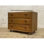 Ercol, a beech chest fitted with three drawers, and moving on castors. H67cm, W92cm, D45cm.