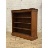 An Edwardian walnut open bookcase, with a figured frieze above three adjustable shelves, raised on a