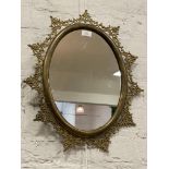 A Vintage gilt brass oval wall hanging mirror with openwork floral border. 55cm x 45cm.