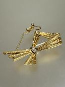 A 1950s/60s 18ct gold modernist brooch with three stands of textured rods knotted with three