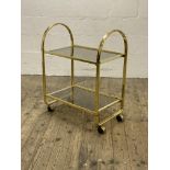A Vintage 1980's two tier gilt metal and smoked glass drinks trolley, moving on castors. H85cm,