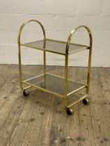 A Vintage 1980's two tier gilt metal and smoked glass drinks trolley, moving on castors. H85cm,