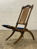 A folding campaign style chair, late 19th century, floral carved crest rail above straw back and