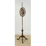 An Edwardian mahogany pole screen, the oval banner with embroidered panel worked in a floral