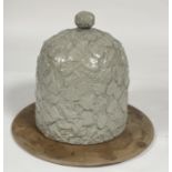 A celadon glazed ceramic cheese dome decorated with ivory leaves on a criss cross background with