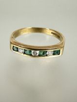 A 9ct gold ring set four circular cut emeralds inter-spaced with three round brilliant cut