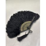 a Edwardian black lacquered and gilt stick ostrich feather evening fan with original cord and tassel