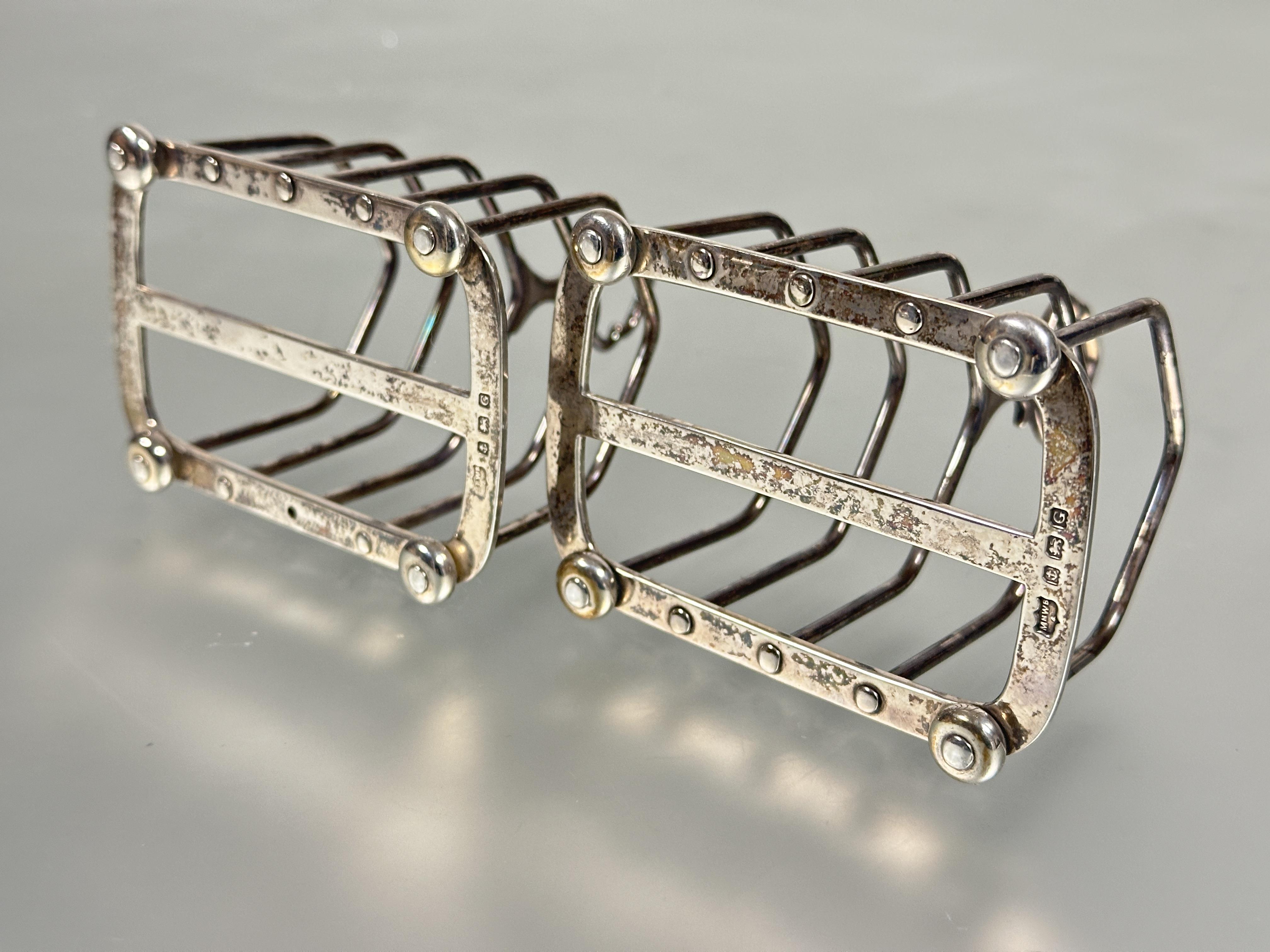 A pair of Birmingham silver four division arched toast racks with handles to top raised on bun - Image 2 of 2