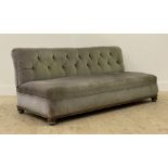 A late Victorian upholstered banquet or bench sofa, covered in deep buttoned green velvet, raised on